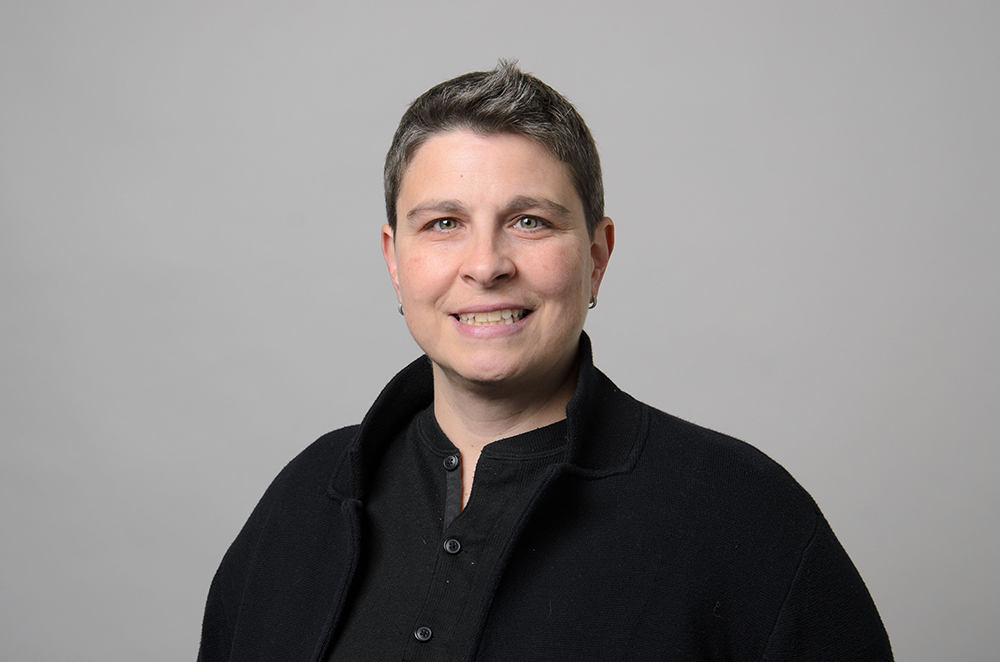 Portrait of Rosa Rizzo wearing a black blazer and black collared shirt.