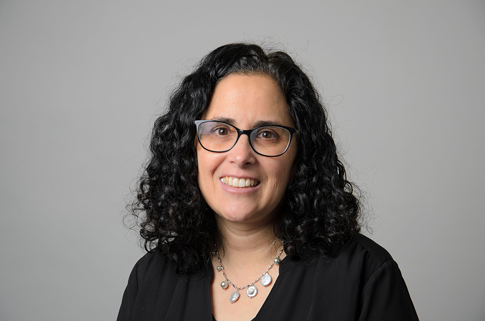 Portrait of Laura Tropp wearing glasses and a blakc blouse.