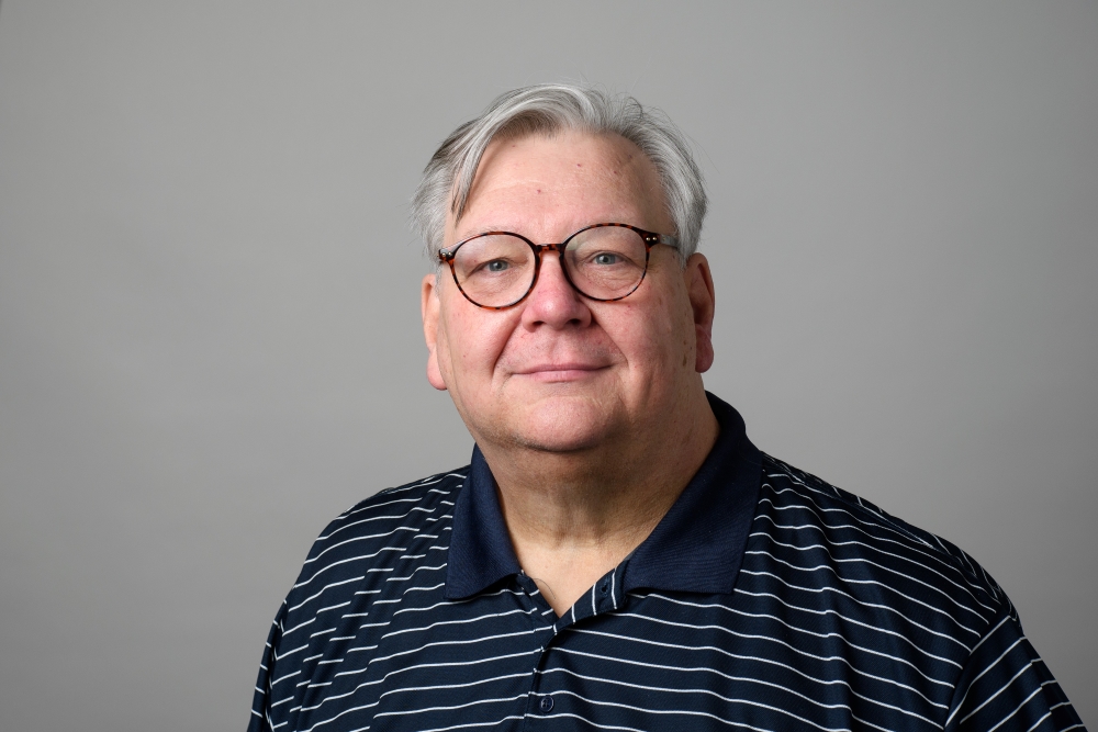 Portrait of William Schwendner wearing glasses and a blue and white stripped shirt.