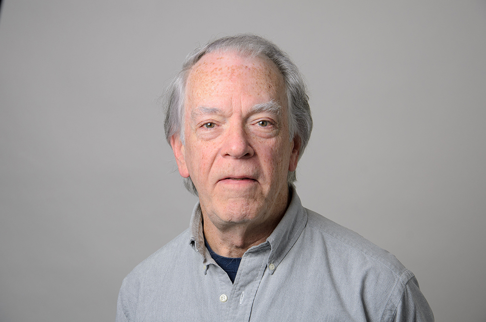 Portrait of John White wearing a gray collared shirt.