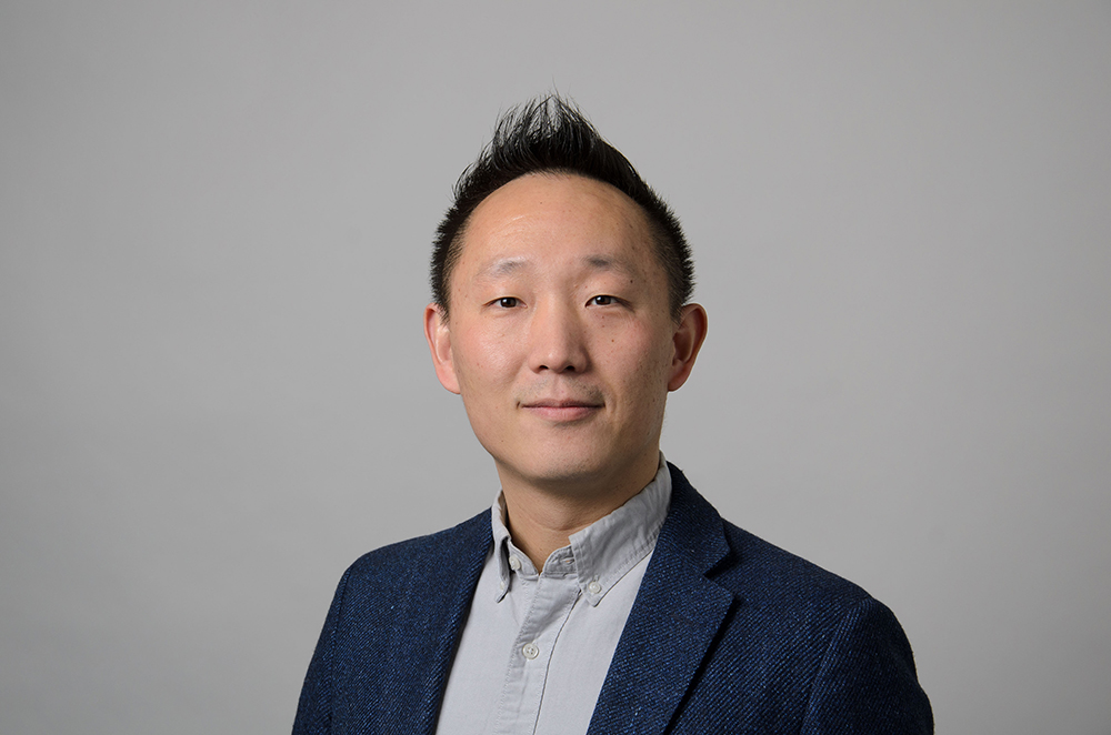 Portrait of Wei Chen wearing a blue blazer and gray collared shirt.