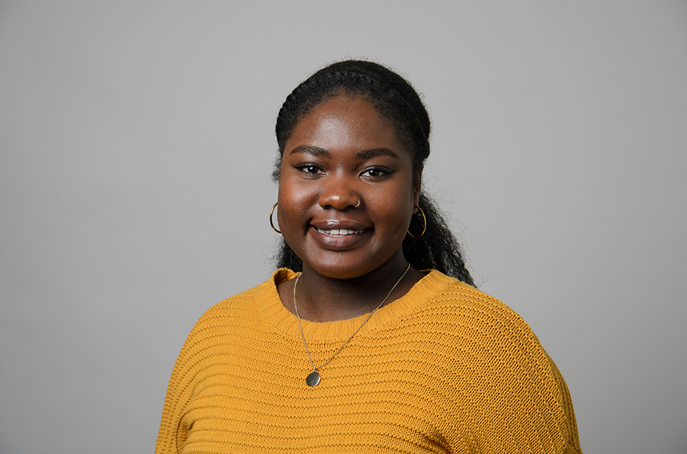 Portrait of Akosua Agyei wearing a yellow sweater.